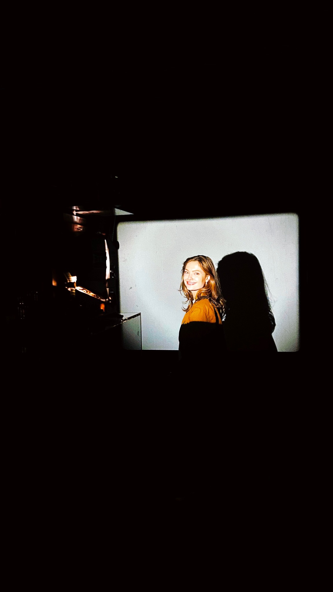 Gabriella Lombardo beside a film projector in warm projected light